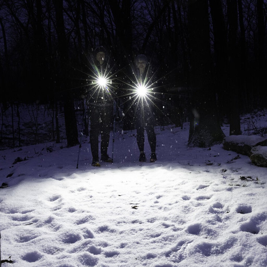 two people standing in the snow with chest lights on